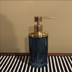 textured blue glass soap dispenser with a gold-tone pump
